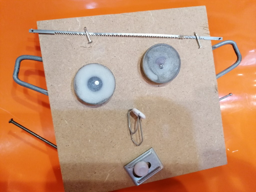 Des pièces disposées sur une planche qui forme un visage