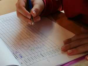 Une main d'enfant remplit la fiche de présences