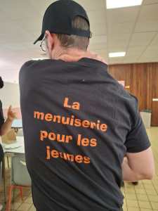 Un animateur de dos qui porte un t-shirt avec le texte : La menuiserie pour les jeunes.