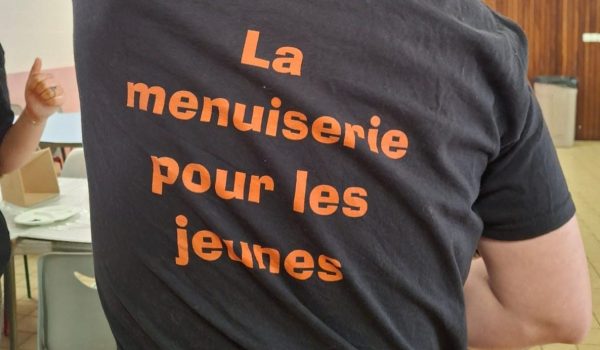 Un animateur de dos qui porte un t-shirt avec le texte : La menuiserie pour les jeunes.
